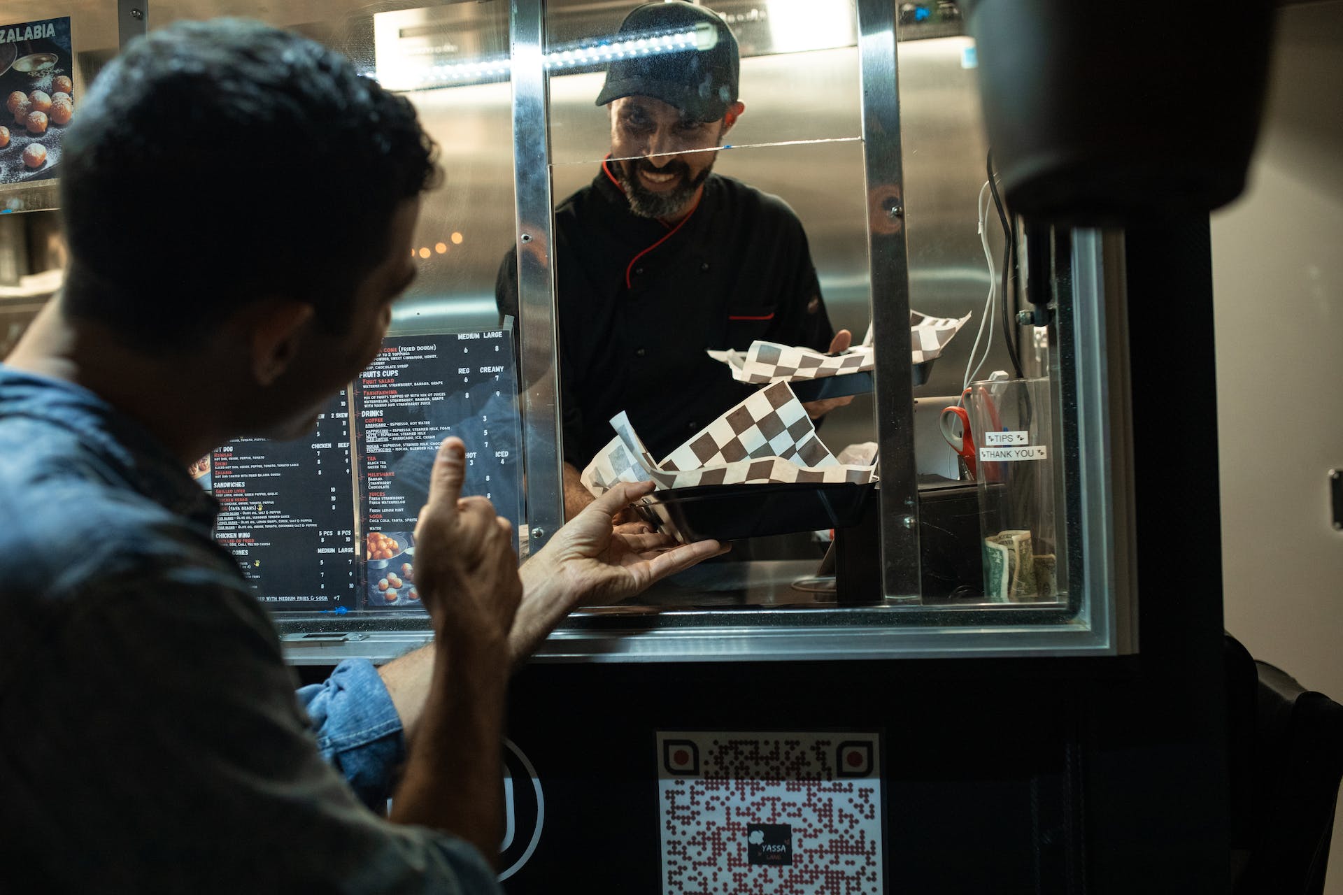 A man giving a food truck chef a thumbs up